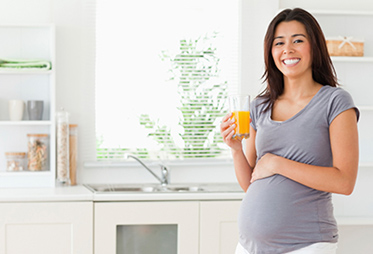 Pregnant Woman in Kitchen Smiling