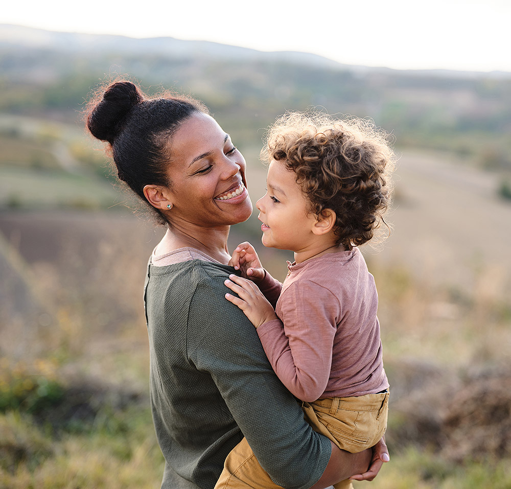 Smiling mother and toddler daughter on a hike